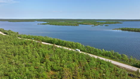 Aerial-view-of-a-Camper-van-driving-at-lake-Inari-in-Lapland,-north-Finland