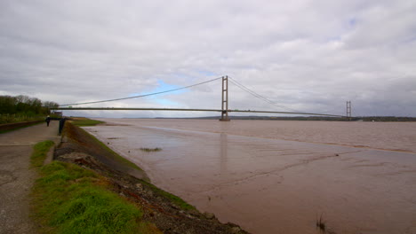 extra-wide-shot-of-the-Humber-bridge-showing-exposed-mud-flats-on-the-Humber-estuary-with-footpath