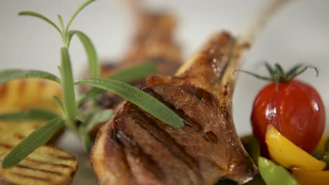 Close-up-of-grilled-lamb-chops-with-fresh-rosemary,-grilled-vegetables,-and-a-cherry-tomato
