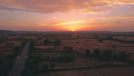 Luftaufnahme-Einer-Drohne-Mit-Wunderschönen-Sonnenuntergangswolken-über-Dem-Horizont-Und-Weizenfarmen-In-Einem-Ländlichen-Dorf-In-Nordindien