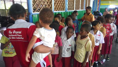 Profesor-Frente-A-Clase-Con-Un-Bebé-En-La-Mano-Sistema-Escolar-Indonesio-Papua