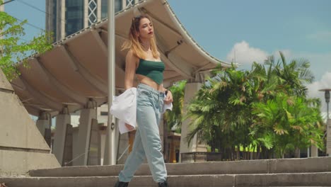 Engaged-in-exploration,-a-girl-in-jeans-and-boots-navigates-through-a-Caribbean-city,-its-skyline-adorned-with-tall-buildings