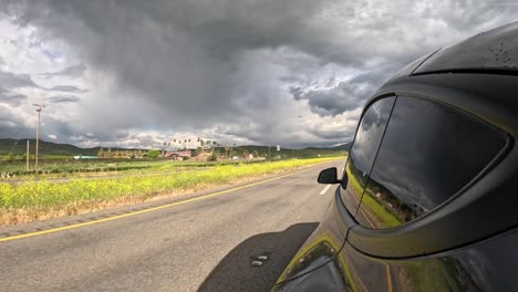 Driving-through-Tehachapi-with-dramatic-clouds,-reflected-car-side-mirror,-time-lapse