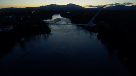 Aerial-footage-panning-up-to-reveal-the-Sundial-Bridge-in-the-dusk-of-sunset-over-the-Sacramento-River-in-Redding,-California