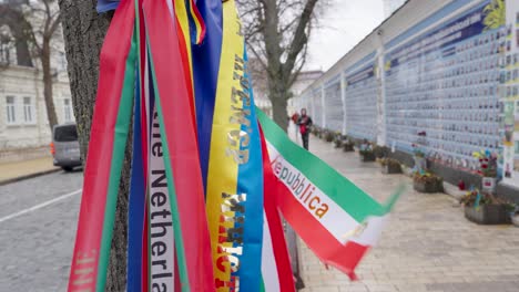 Banderas-Festivas-De-Poliéster-De-Tela-Brillante-Y-Vibrante-Ondean-En-El-Viento-Junto-Al-Muro-Del-Recuerdo-Kiev,-Ucrania