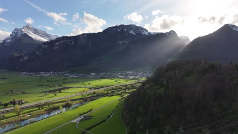 Sunlight-beams-over-Weesen,-Switzerland,-green-fields-and-mountains