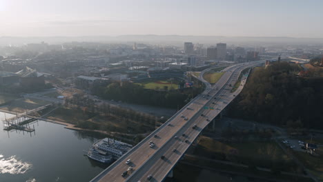 Wide-aerial-footage-of-busy-traffic-on-the-Williams-Memorial-Bridge-on-Highway-27-in-Chattanooga,-TN-with-downtown-in-the-background-during-sunrise