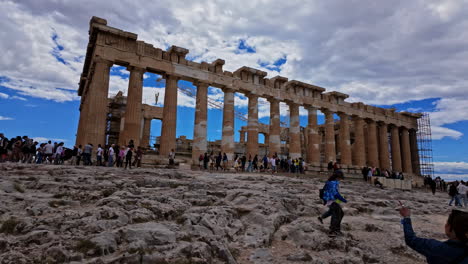 Slow-motion-shot-of-tourists-around-monument-of-Agrippa-and-Propylaia,-Acropolis,-Athens,-Greece-on-a-cloudy-day