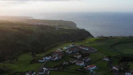 Aufsteigende-Drohnenaufnahmen-Der-üppig-Grünen-Vulkaninsellandschaft-Mit-Meer-Und-Häusern-Auf-Der-Azoreninsel-Sao-Miguel