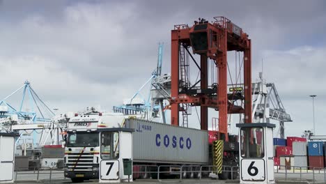 Geschäftige-Hafenszene-Mit-Kränen,-Die-Container-Auf-Lastwagen-Laden,-Lebhafte-Industrietätigkeit