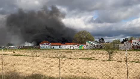 Von-Einem-Fahrzeug-Aus-Sehen-Wir-Einen-Großen-Brand,-Der-In-Leganes-Madrid-Ausgebrochen-Ist.-Die-Feuerwehr-Und-Die-Polizei-Sind-Voll-Im-Einsatz.-Ihre-Fahrzeuge-Sind-Geparkt-Und-Wir-Sehen-Einen-Feuerwehrmann,-Der-Das-Feuer-Löscht.