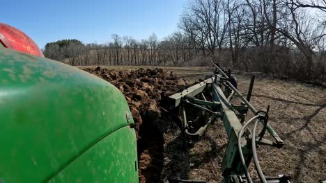POV---Farmer-on-green-agricultural-tractor-prepares-field-for-planting-and-lowers-plows-at-beginning-of-row