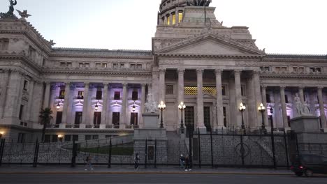 Wide-shot-of-the-illuminated-National-Congress-of-Argentina-at-dusk,-traffic-passing-by