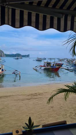 Vertical-Video,-El-Nido-Philippines,-Beach-and-Balangay-Boats,-Panoramic-View-From-Beachfront-Restaurant