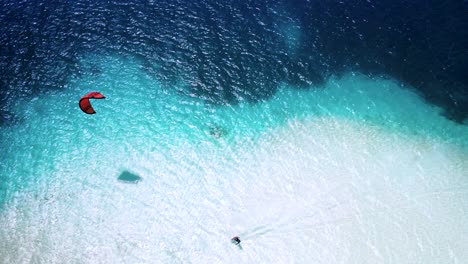 A-person-kiteboarding-in-crystal-clear-turquoise-waters,-vibrant-contrast,-aerial-view