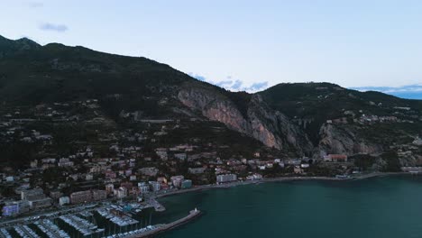 Menton-on-the-french-riviera,-highlighting-its-coastal-beauty-and-nestled-mountains-at-dusk,-aerial-view