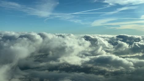 Pilot-POV-shot-from-an-airplane-cockpit-flying-across-a-sky-with-some-fluffy-clouds-at-the-golden-minute-with-some-wakes-in-a-blue-sky