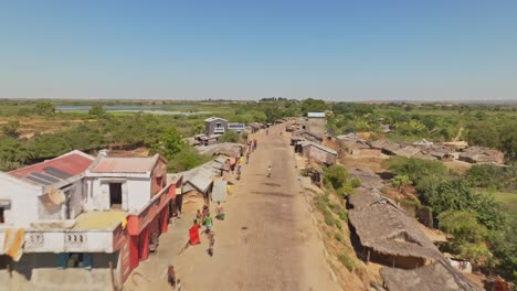 Aerial-drone-shot-of-village-with-traditional-houses-along-a-road-in-Madagascar-countryside-with-rice-fields