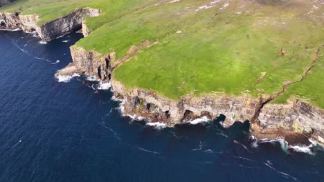 Aerial-View-of-Picturesque-Coastline-of-Scotland,-United-Kingdom-on-Sunny-Day,-Cliffs-Above-Sea-and-Green-Land