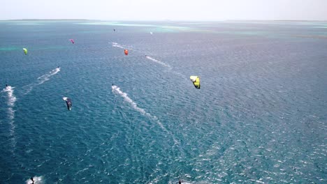 A-colorful-kite-surfer-gliding-over-clear-turquoise-waters,-vibrant-and-dynamic-ocean-scene,-aerial-view