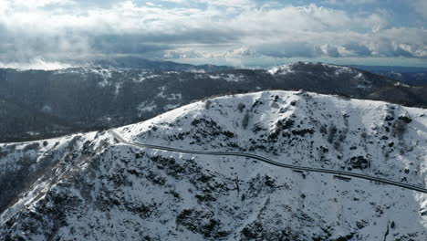 Ein-Schneebedeckter-Berg-Mit-Seilbahnen,-Wolken-Im-Hintergrund,-Luftaufnahme