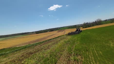 Green-farm-fields-and-Plowing-Machinery-at-work-during-sunny-day-in-American-countryside