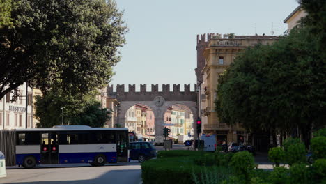 Sunny-day-in-Verona-with-ancient-city-gate-and-bustling-street-life