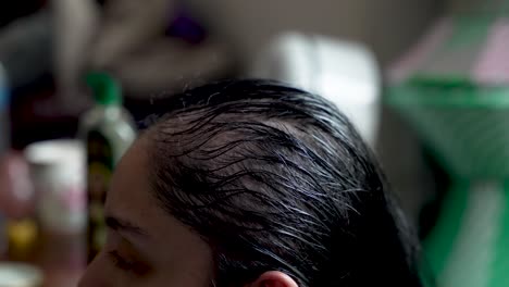 Close-up-of-hands-applying-oil-to-a-person's-hair,-emphasizing-the-texture-and-shine