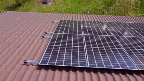Kamerafahrt-Einer-Reihe-Von-Solarmodulen-Für-Verbraucher-Auf-Einem-Wohngebäude,-Die-Nachhaltige-Energie-Erzeugen-Und-Auf-Einem-Roten-Ziegeldach-Montiert-Sind