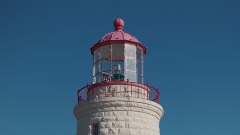 Red-and-white-lighthouse-against-a-clear-blue-sky,-detailed-close-up-of-the-lantern-room