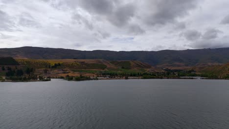 Lake-dunstan-in-central-otago-with-cloudy-skies-and-rugged-terrain,-aerial-view