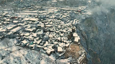Pan-aerial-shot-of-snow-covered-Karimabad-town-in-Hunza,-Pakistan