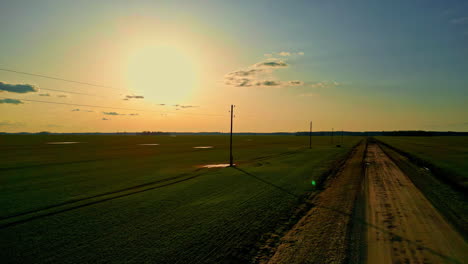 Tranquil-countryside-landscape-featuring-road,-sunset,-and-power-poles