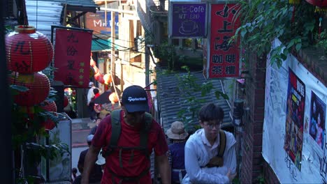 People-navigate-through-narrow-and-steep-staircases-lined-with-restaurants-and-shops,-exploring-the-quaint-mountain-village-town-of-Jiufen's-Old-Street,-New-Taipei-City,-Taiwan