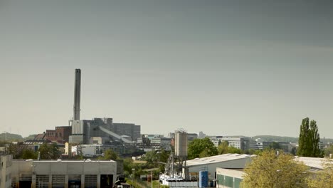 Un-Amplio-Paisaje-Urbano-Que-Muestra-Una-Planta-Industrial-Con-Altas-Chimeneas-Bajo-Un-Cielo-Azul-Claro