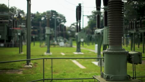 Two-engineers-inspect-equipment-at-a-power-substation,-shallow-focus-on-foreground