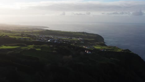 Drohnenaufnahmen-Einer-Subtropischen-Vulkaninsellandschaft-Bei-Sonnenuntergang-Mit-Häusern-In-Der-Nähe-Von-Meeresklippen-Auf-Der-Azoreninsel-Sao-Miguel