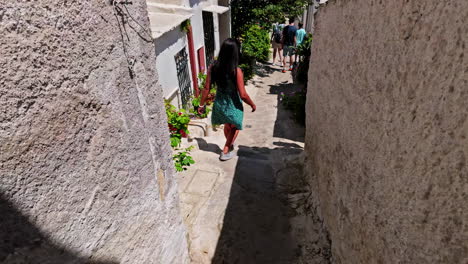 Tourists-walking-narrow-streets-of-Anafiotika,-slow-motion-follow-shot-from-behind