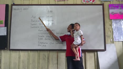 Profesor-Enseñando-Clase-Con-Un-Bebé-En-La-Mano-Sistema-Escolar-Papú