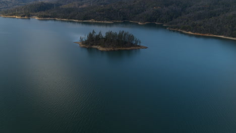 Aerial-pan-up-over-Whiskeytown-Lake-in-northern-california-revealing-an-island-and-mountains-in-the-background