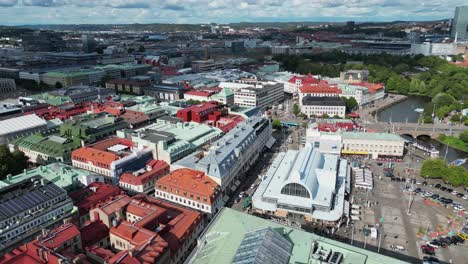 Aerial-orbits-public-market-by-city-canal-in-sunny-Gothenburg,-Sweden
