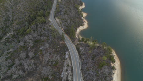 Aerial-flyover-of-a-road-that-follows-the-coast-of-Whiskeytown-Lake-in-California