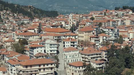 Drone-flying-close-up,-above-a-village-on-a-green-hill-in-Europe,-red-roof-tops,-little-houses,-sunny-weather,-Greece-4K-video