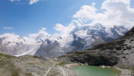 Flight-towards-the-beautiful-Swiss-Alps-over-a-small-glacial-lake-in-Zermatt,-Switzerland,-Europe