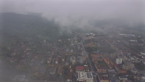 4K-Filmmaterial-Aus-Der-Luft-Mit-Drohnen,-Die-Bei-Regen-In-Der-Stadt-In-Den-Regenwolken-Fliegen,-Mit-Bergen-Im-Hintergrund