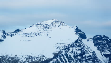 Snow-capped-mountain-peak-in-Iceland-during-a-serene-timelapse,-capturing-shifting-clouds-and-light