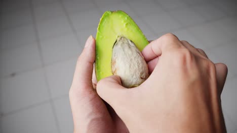 Person-Taking-The-Seed-On-A-Half-Slice-Fresh-Avocado