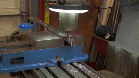This-video-shows-a-vertical-Mill-in-a-machine-shop-that-is-in-the-process-of-cutting-metal-from-the-end-of-a-square-bar-with-metal-chips-flying-off