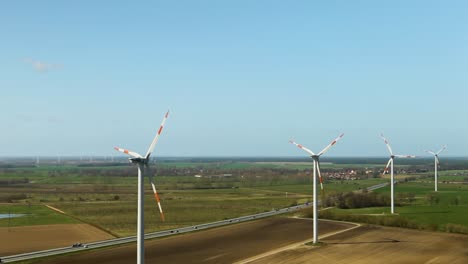 Wind-turbines-spin-gently-on-a-sunny-day-over-lush-farmland,-showcasing-sustainable-energy