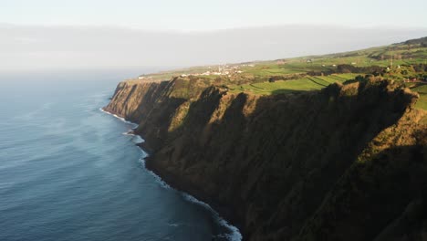 Imágenes-De-Drones-De-La-Exuberante-Campiña-Verde-De-La-Isla-Volcánica-Con-Luz-Solar-Brillante-Y-Casas-Cerca-Del-Acantilado-Del-Océano-En-La-Isla-De-Sao-Miguel-De-Las-Azores